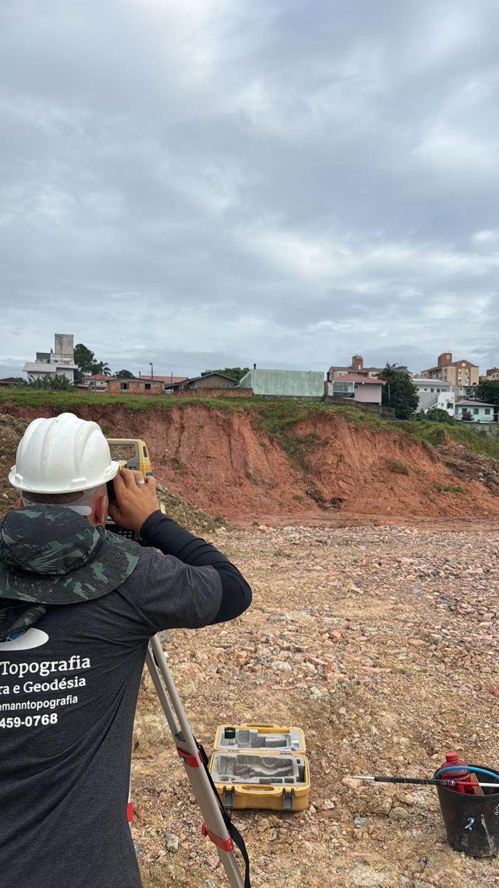 Profissional realizando medição topográfica em terreno de obra